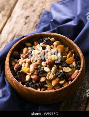 Sentiero sano mix snack fatti di dadi (noci, mandorle, arachidi e frutta secca (uva passa, uva sultanina) nella ciotola di legno (messa a fuoco selettiva) Foto Stock