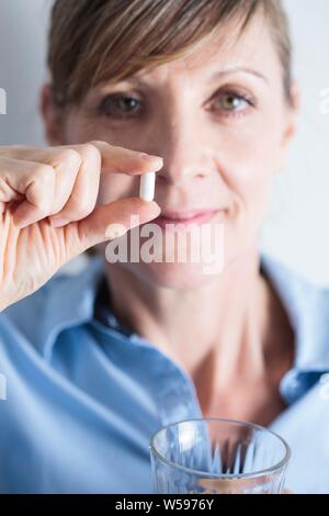Donna che mantiene un ibuprofene compressa fra le dita. Foto Stock