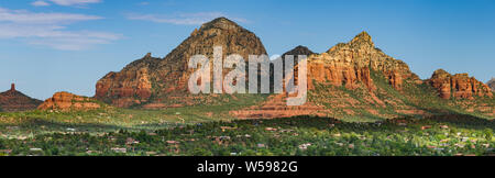 Il bellissimo panorama di colorati picchi di arenaria e le scogliere di prima mattina di luce sopra il verde di alberi, edifici e case nella città di Sedona, in Arizona Foto Stock