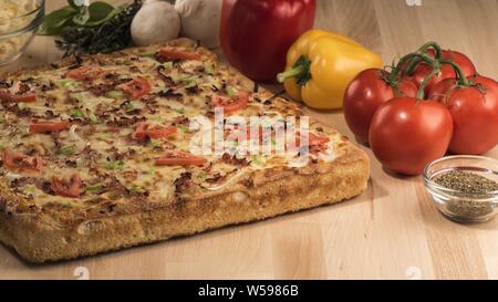 Primo piano di una pizza quadrata con pomodori freschi, peperoni, funghi e spezie Foto Stock