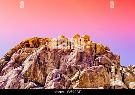 Colorato arancione, rosa, viola cieli del deserto rock formazione al tramonto. Foto Stock