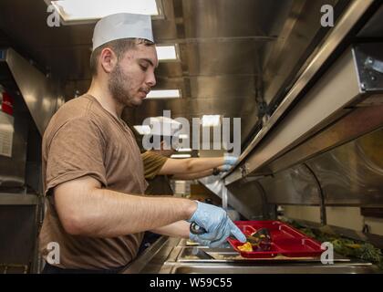 190725-N-KG461-1053 GOLFO ARABICO (24 luglio 2019) le operazioni specialista di terza classe Mario Cortez, da La Puente, Calif. assegnato a Amphibious Assault nave USS Boxer (LHD 4), serve cibo per i marinai e marines in disordine deck dinette, luglio 25, 2019. Boxer è parte del Boxer anfibio gruppo pronto e undicesimo Marine Expeditionary Unit ed è distribuito negli Stati Uniti Quinta Flotta area di operazioni a sostegno di operazioni navali per garantire stabilità marittimo e la sicurezza nella regione centrale di collegamento del Mediterraneo e del Pacifico attraverso l'Oceano Indiano occidentale e tre strategici punti di strozzatura. ( Foto Stock