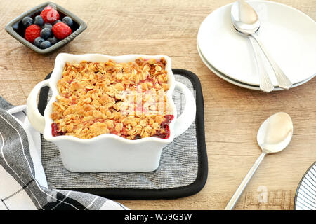 Sfornato fresco Lampone Mirtillo crumble per due in bianco piccola casseruola in formato orizzontale. Deliziosi piatti di stagione freschi dessert berry. Foto Stock