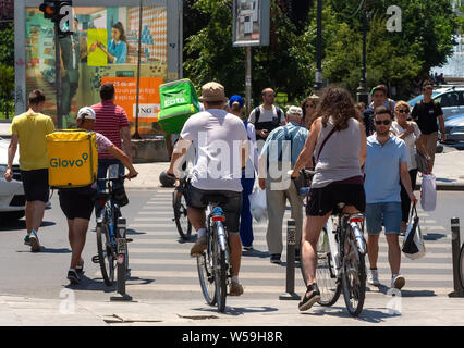 Bucarest, Romania - 27 Giugno 2019: Uber mangia e Glovo Consegna del cibo ai corrieri di attraversare la strada lungo con altri ciclisti e pedoni a Bucarest Foto Stock