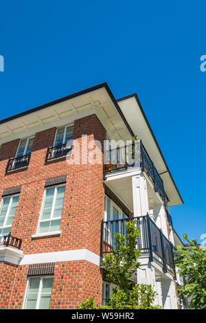L'angolo dell'edificio di appartamenti nuovi di zecca sul cielo blu sullo sfondo Foto Stock