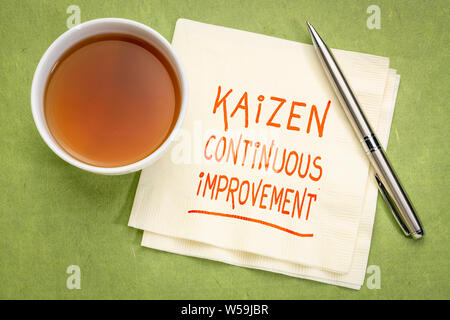 Kaizen - giapponese il miglioramento continuo concetto - scrittura su un tovagliolo con una tazza di tè Foto Stock