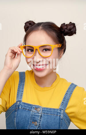 Piuttosto attraente giovane donna asiatica tenendo gli occhiali con due capelli-panini Foto Stock