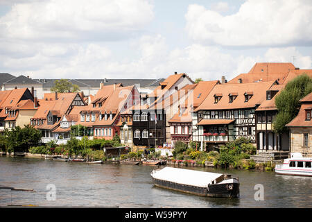 Le case e gli edifici lungo il fiume Regnitz a Bamberg in Germania, con una chiatta in primo piano. Foto Stock