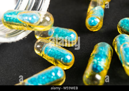 Le capsule di gelatina con il farmaco disperse dalla bottiglia sul tavolo. Foto Stock