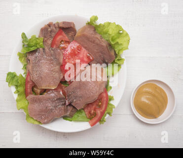 Fette di lingua di manzo con pomodoro e senape su sfondo di legno Foto Stock