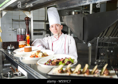 Ritratto di uno chef con il cibo cotto in cucina nel ristorante Foto Stock