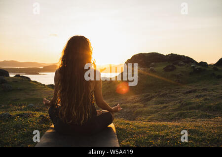 Donna meditazione yoga da soli a sunrise montagne. Vista da dietro. Lo stile di vita di viaggio spirituale il concetto di rilassamento. Armonia con la natura. Foto Stock