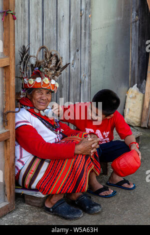 Un giovane ragazzo è affascinato dal costume indossato da un Ifugao femmina tribale, Banaue, Luzon, Filippine Foto Stock