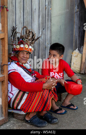 Un giovane ragazzo è affascinato dal costume indossato da un Ifugao femmina tribale, Banaue, Luzon, Filippine Foto Stock