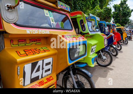 Una fila di coloratissimi tricicli, Alona Beach, Bohol, Filippine Foto Stock