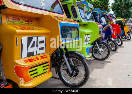 Una fila di coloratissimi tricicli, Alona Beach, Bohol, Filippine Foto Stock