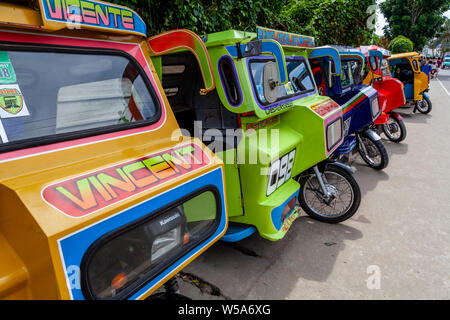 Una fila di coloratissimi tricicli, Alona Beach, Bohol, Filippine Foto Stock