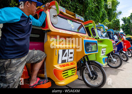 Una fila di coloratissimi tricicli, Alona Beach, Bohol, Filippine Foto Stock