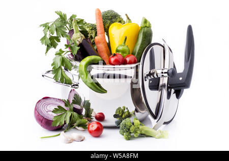 Verdure miste e gli ingredienti nella pentola a pressione sullo sfondo bianco Foto Stock