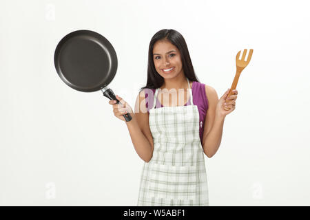 Donna che mantiene padella e sorridente Foto Stock