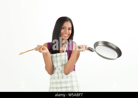 Donna che mantiene padella e sorridente Foto Stock