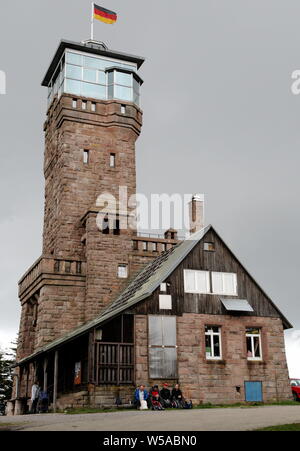 Turisti che si siedono sulla parte anteriore della torre Hornisgrinde, Mummelsee, Black Forest, Germania Foto Stock