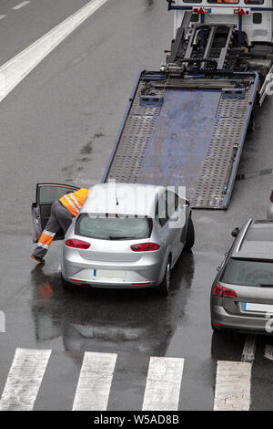 Scena di un carrello di traino con piattaforma abbassata pronto a caricare ripartiti in auto su una strada di città strada. Servizio stradale. Spazio di copia Foto Stock