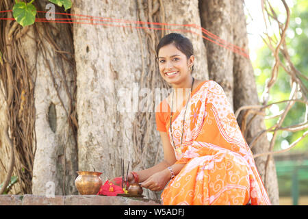 Donna adorare un albero sacro e sorridente Foto Stock