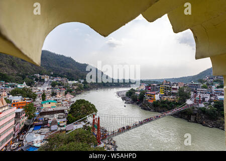 Vista di Laxman Jhula attraverso il Fiume Gange nella città spirituale di Rishikesh nello stato di Uttarakhand in India Foto Stock