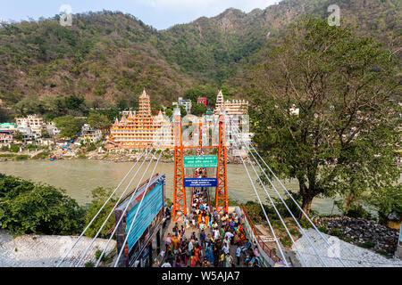 Vista di Laxman Jhula attraverso il Fiume Gange nella città spirituale di Rishikesh nello stato di Uttarakhand in India Foto Stock