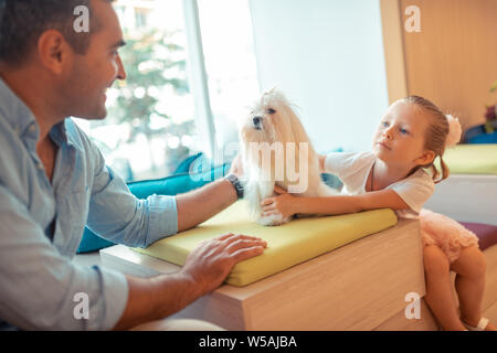 Figlia di parlare a papà e toccando i loro soffici cane Foto Stock