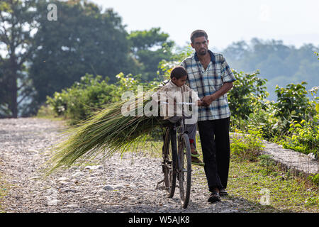 Un uomo porta suo figlio su un ciclo nella zona rurale di Rishikesh, una santa città nello stato di Uttarakhand in India Foto Stock