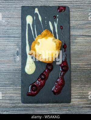 Colpo verticale di un deserto con creme su un nero vassoio su una superficie di legno Foto Stock