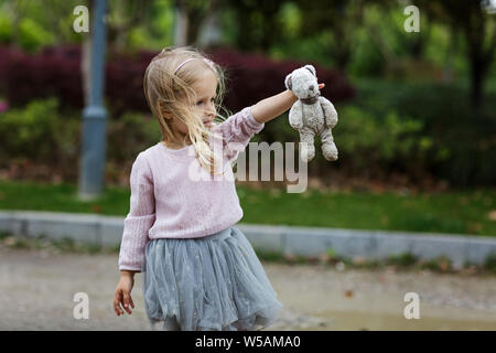 Bellissima bambina in una gonna tutu tenendo un orsacchiotto di peluche outdoor Foto Stock