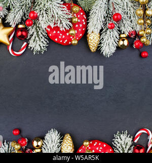 Sfondo di Natale carta verde con albero di Natale ramoscello, rosso baubles, garland e nuovo anno di decorazione su sfondo nero Foto Stock