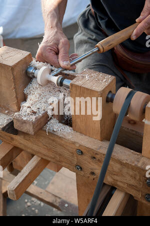 Un artigiano si ritaglia un pezzo di legno utilizzando un tornio manuale Foto Stock