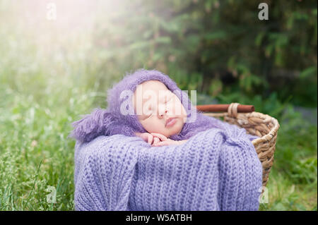 Inizio della vita e felice fairy magic concetto di infanzia. 17 giorno vecchio sorridente neonato dorme sul suo stomaco nel cestello nella natura in g Foto Stock