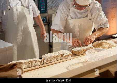 Baker mettere focacce sulla buccia prima della cottura Foto Stock