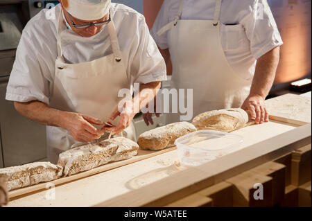 Baker mettere focacce sulla buccia prima della cottura Foto Stock