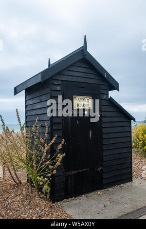 Vecchia casa di fumo sul bordo della spiaggia Foto Stock