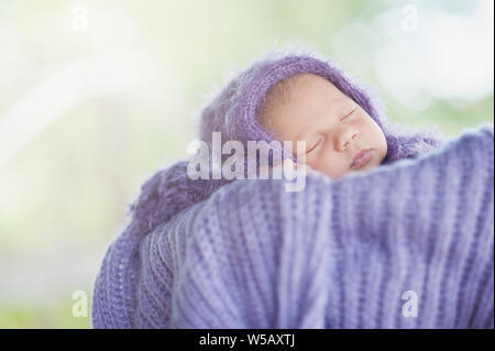 Inizio della vita e felice fairy magic concetto di infanzia. 17 giorno vecchio sorridente neonato dorme sul suo stomaco nel cestello nella natura in g Foto Stock