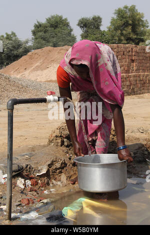 Donna raccolta di acqua da un rubinetto di acqua Foto Stock