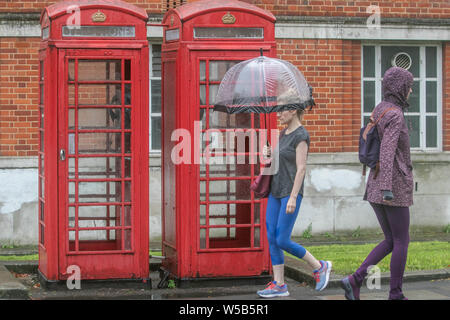 Londra, Regno Unito. 27 Luglio, 2019. Un pedone ripari sotto un ombrello a Wimbledon a sud-ovest di Londra in un umido del mattino come le condizioni meteorologiche si raffredda dopo la rottura di record ondata di caldo in London Credit: Amer Ghazzal SOPA/images/ZUMA filo/Alamy Live News Foto Stock