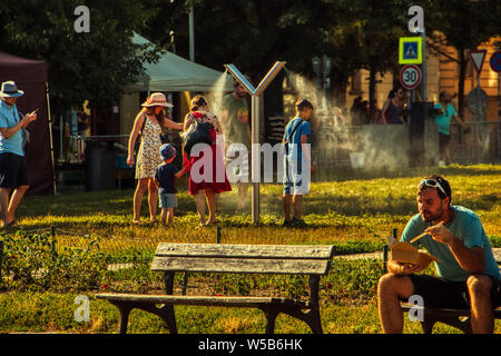 Praga, 27 luglio 2019. La gente si raffredda al sole nella nebbia di pubblico machina a Park in Europa onda di calore Foto Stock