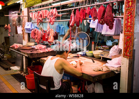 Butcher mettendo in pausa per mangiare a Fa Yuen mercato. Hong Kong Foto Stock