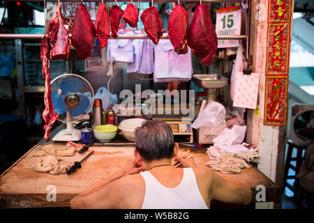 Butcher mettendo in pausa per mangiare a Fa Yuen mercato. Hong Kong Foto Stock