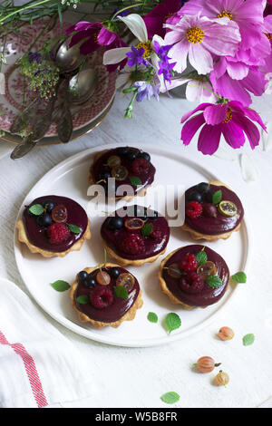 Tartine di frollette con crema di frutti di bosco e fiori su sfondo chiaro. Foto Stock