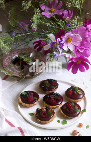 Tartine di frollette con crema di frutti di bosco e fiori su sfondo chiaro. Foto Stock