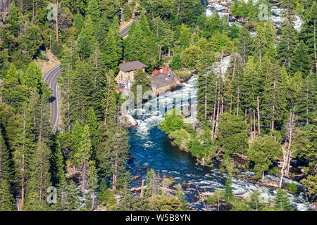 Vista aerea del fiume Merced fluente attraverso una foresta di conifere; energia elettrica ferroviaria e strada asfaltata visibile sulla sinistra; Yosemite National Park, CA Foto Stock