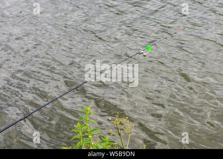 Canna da pesca con una campana in acqua, pesca in estate Foto Stock